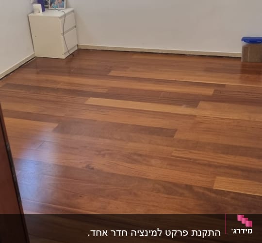 רצפת פרקט עץ כהה בחדר ריק עם קיר לבן
